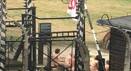 Personas desnudas sacrifican cordero frente al campo nazi en Auschwitz