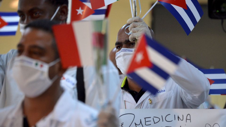 Médicos cubanos ondean banderas cubanas.