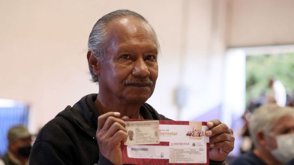 Un hombre de la tercera edad es fotografiado al recibir su tarjeta bancaria para que pueda cobra su Pension para el Bienestar.