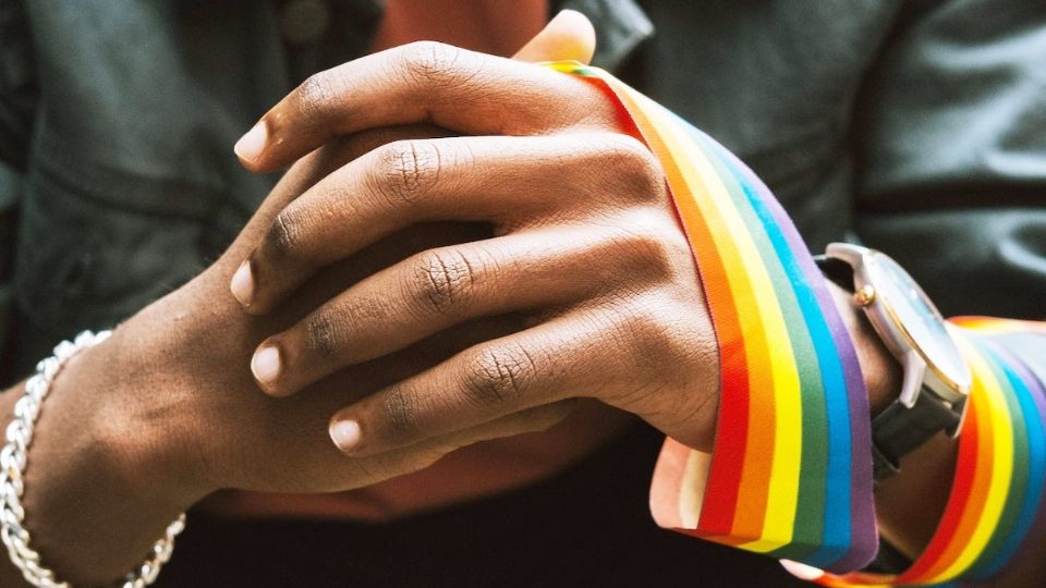 Persona con listón de colores de la bandera LGBT.