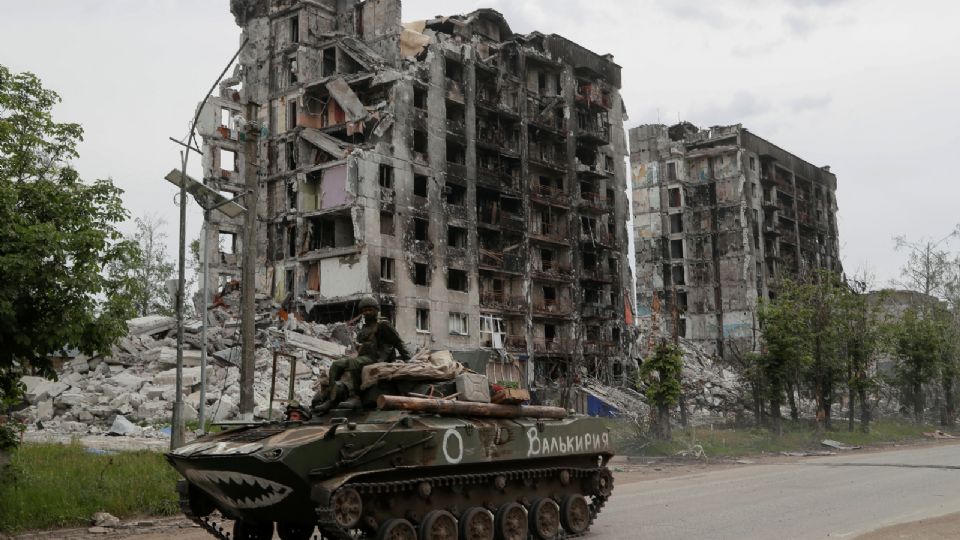 Miembros de las fuerzas armadas prorrusas en un vehículo acorazado frente a edificios destruidos.