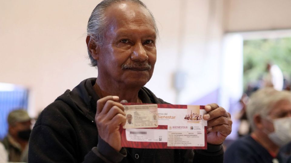 Un hombre de la tercera edad recibe su tarjeta bancaria para que pueda cobrar su Pensión para el Bienestar.