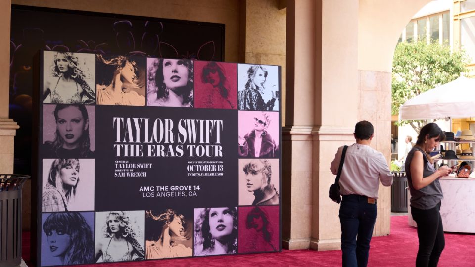 La gente camina junto a un cartel que anuncia la película 'Taylor Swift: The Eras Tour' en un teatro de Los Ángeles.