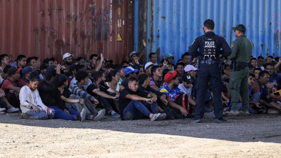 Un oficial de la policía de Aduanas de Estados Unidos y un oficial de la Patrulla Fronteriza reúnen a migrantes en Shelby Park, en Eagle Pass, Texas.