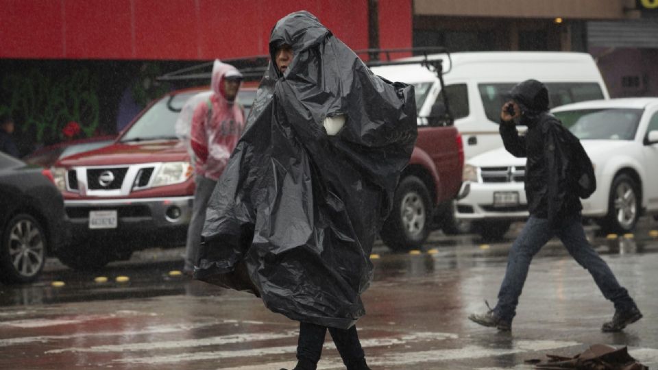 Persona cubriéndose de las lluvias con impermeable improvisado con bolsa.
