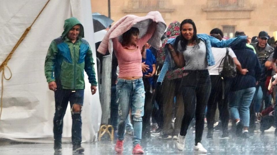 Capitalinos se cubrieron de las lluvias en el Zócalo capitalino.