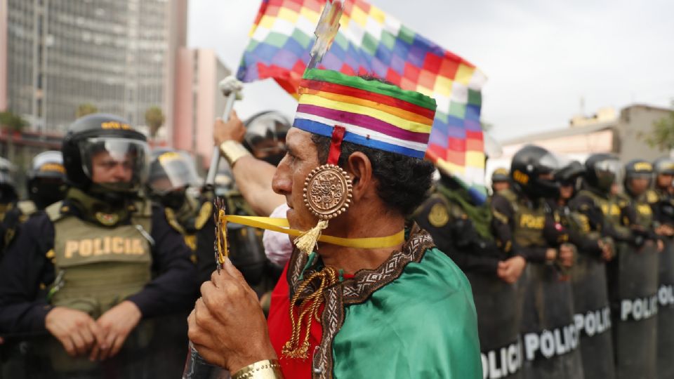 Un hombre agita la bandera wiphala de los pueblos indígenas frente a varios policías que bloquean una marcha que se dirigía al Congreso, al margen de la llamada 'toma de Lima', en Lima.