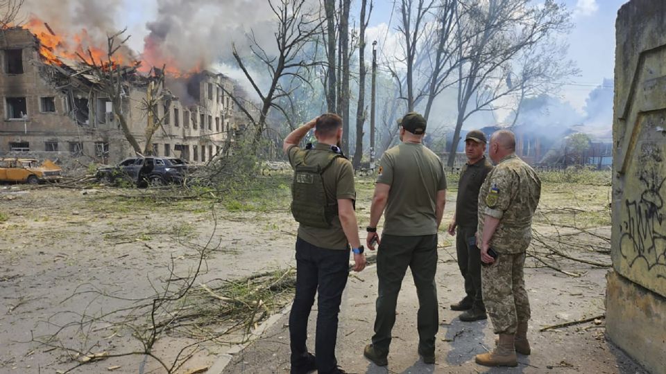 Foto proporcionada por la Policía Nacional de Ucrania de funcionarios ucranianos de pie cerca de una clínica destruida después de un bombardeo en Dnipro, Ucrania central