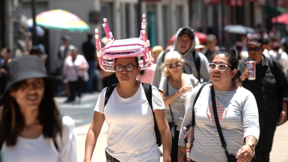 Personas se protegen del sol mientras caminan en las calles principales del Centro Histórico.