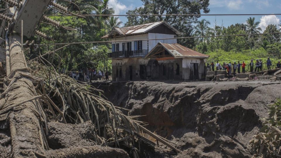 Los aldeanos se encuentran cerca de una casa dañada tras una inundación repentina en Tanah Datar, Sumatra Occidental, Indonesia.