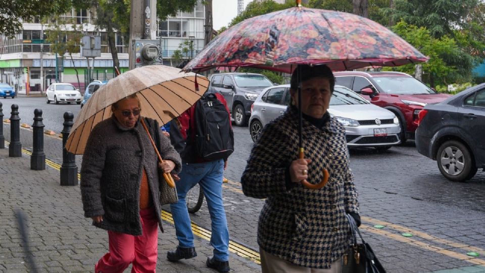 Dos mujeres con paraguas caminan en la capital mexiquense ante las lluvias intermitentes que se han registrado durante este día.