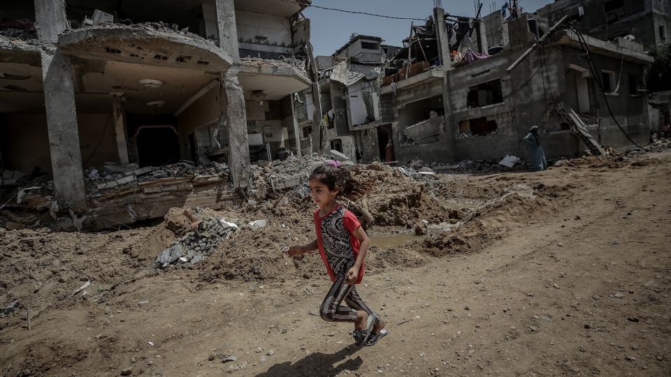 Una niña palestina corre cerca a la destruida casa de su familia