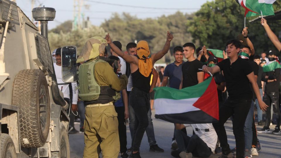 Jóvenes palestinos protestan ante un soldado israelí