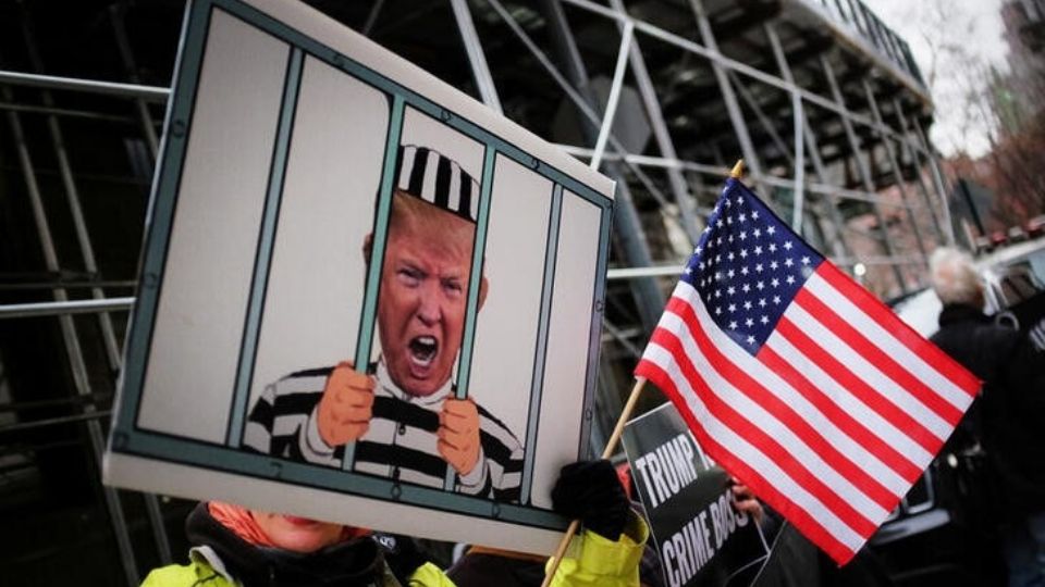 Un manifestante protesta contra el expresidente Donald Trump al exterior de la oficina del fiscal del distrito de Manhattan