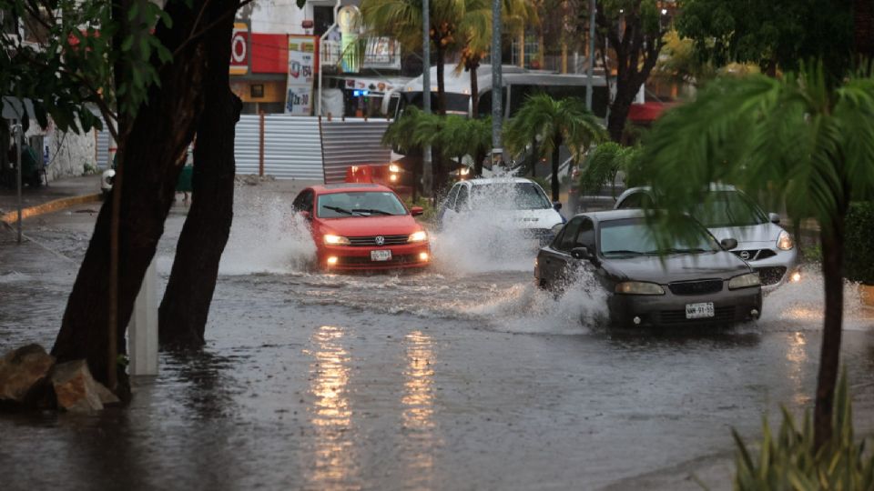 Vehículos transitan por una calle inundada debido a las fuertes lluvias hoy, en el balneario de Acapulco, estado de Guerrero.