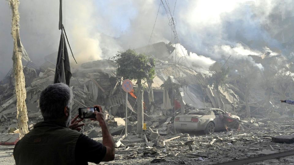 Un hombre fotografía un edificio humeante después de un ataque aéreo israelí sobre el barrio de Dahieh, uno de los bastiones de Hizbulá, en Beirut (El Líbano) estes jueves.