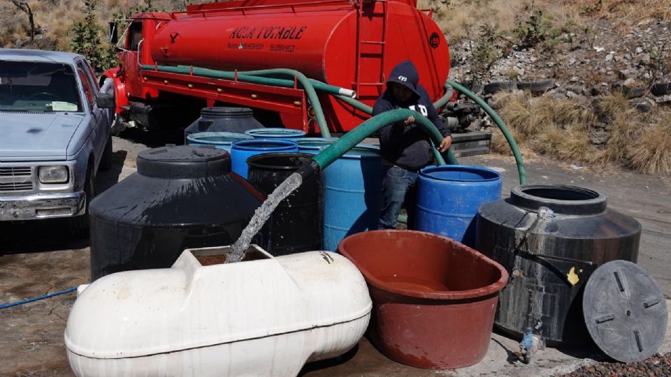 Un señor que transporta agua potable en una pipa suministra botes y tinacos afuera de una casa en el predio Yuguelito, alcaldía Iztapalapa.