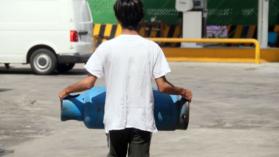 Un joven carga un cilindro de gas que sera llenado en una estacion de servicio.