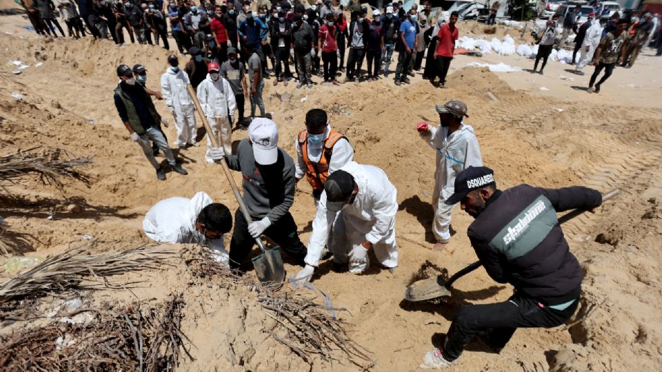 Varias personas trabajan para trasladar a un cementerio los cuerpos de los palestinos muertos durante la ofensiva militar israelí y enterrados en el hospital Nasser.
