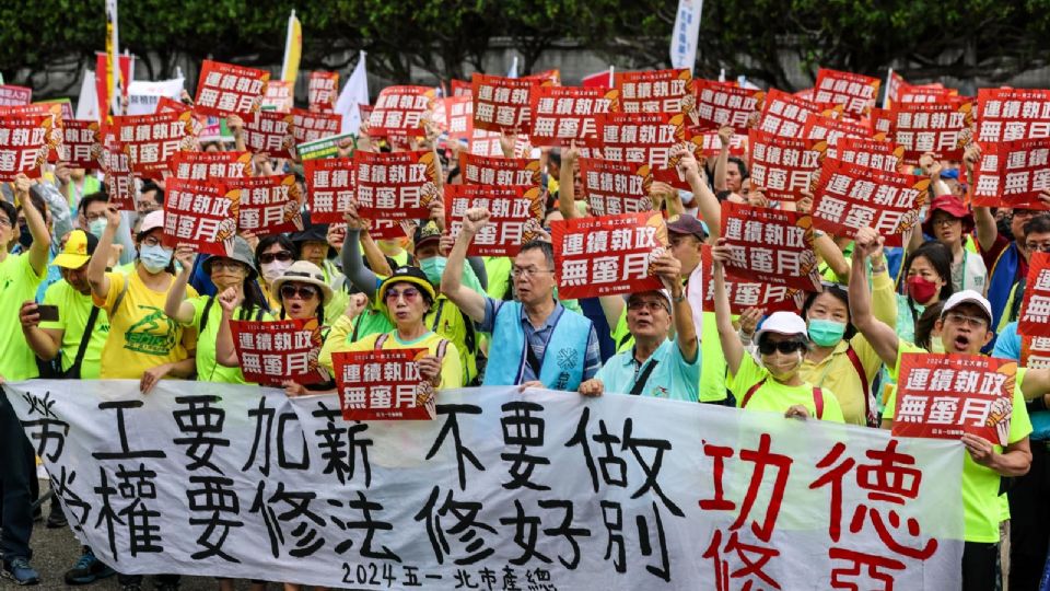 Trabajadores taiwaneses y extranjeros exhiben varias pancartas mientras marchan durante el Día Internacional del Trabajo en Taipei.