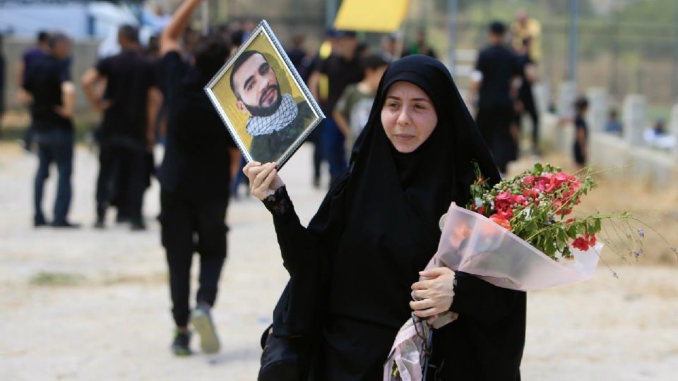 Una mujer sosteniendo una fotografía de un hombre muerto en el conflicto entre Hezbolá e Israel.
