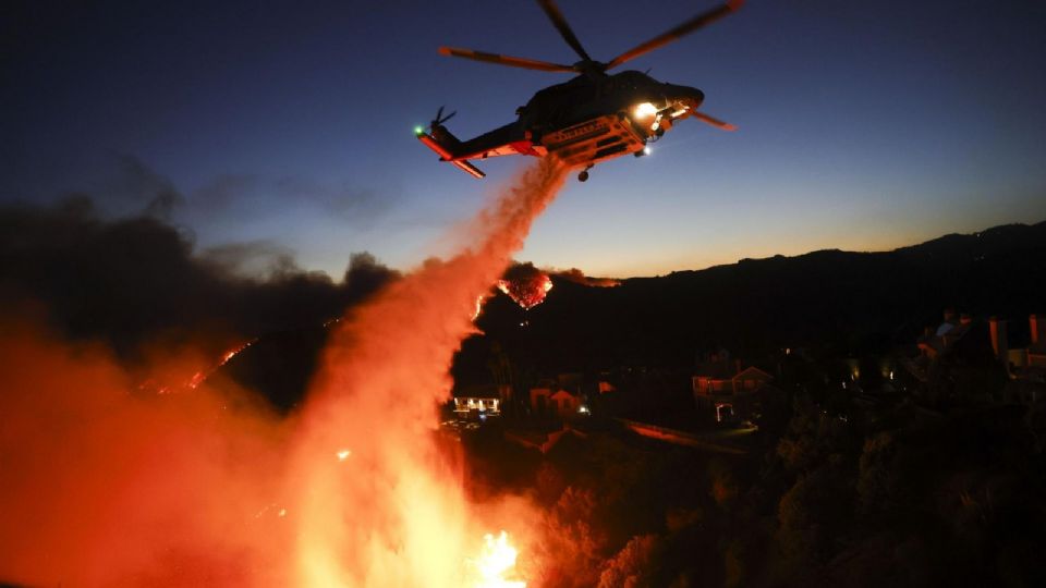 Un helicóptero de bomberos del condado de Los Ángeles arroja agua para combatir el incendio forestal de Palisades en Pacific Palisades, California.