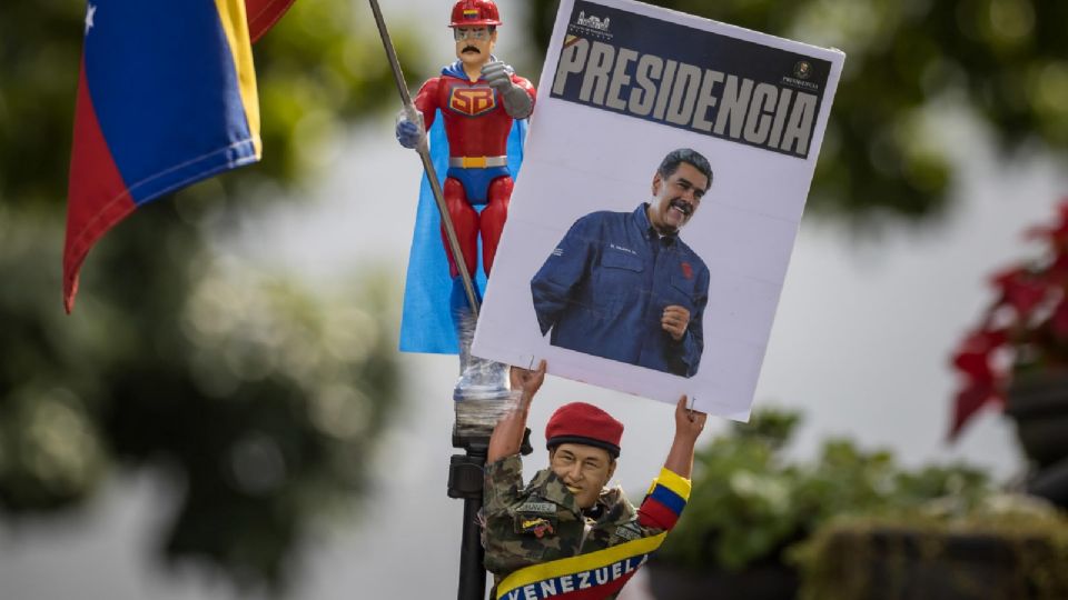 Una persona sostiene un muñeco que representa al fallecido presidente de Venezuela Hugo Chávez con un cartel con la imagen del presidente de Venezuela, Nicolás Maduro.