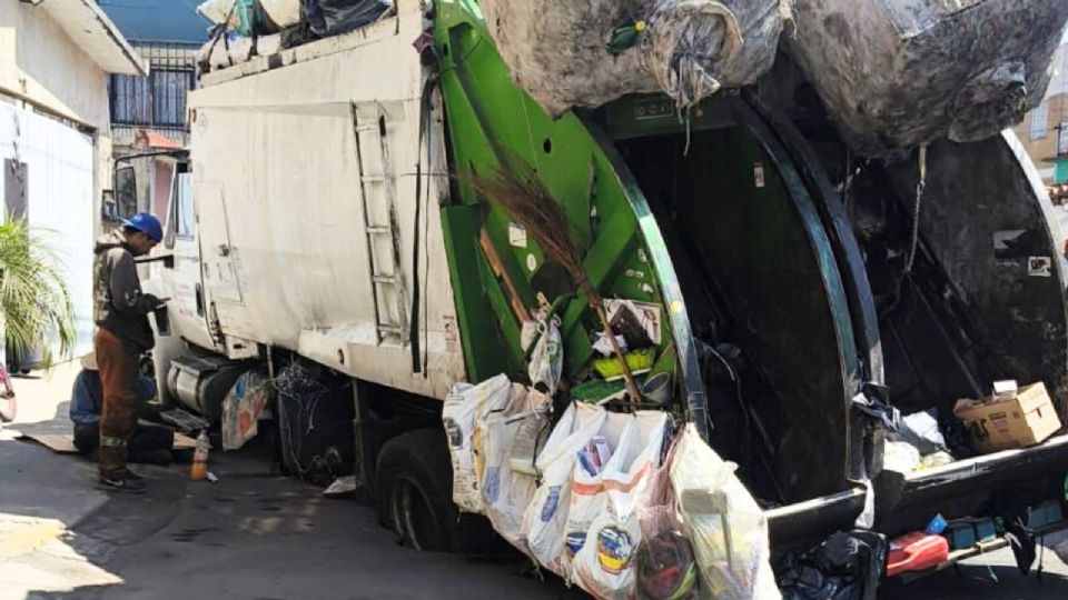Debido al peso y al riesgo de que se abra más el pavimento, el neumático del eje trasero quedó en la oquedad.