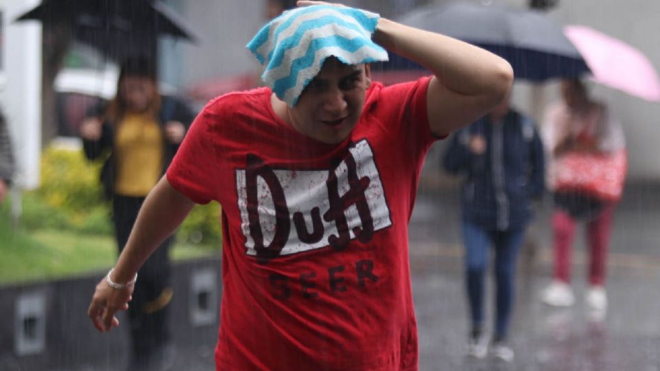 Un joven se cubre de la lluvia con un trapo en la cabeza en la alcaldía Iztapalapa.