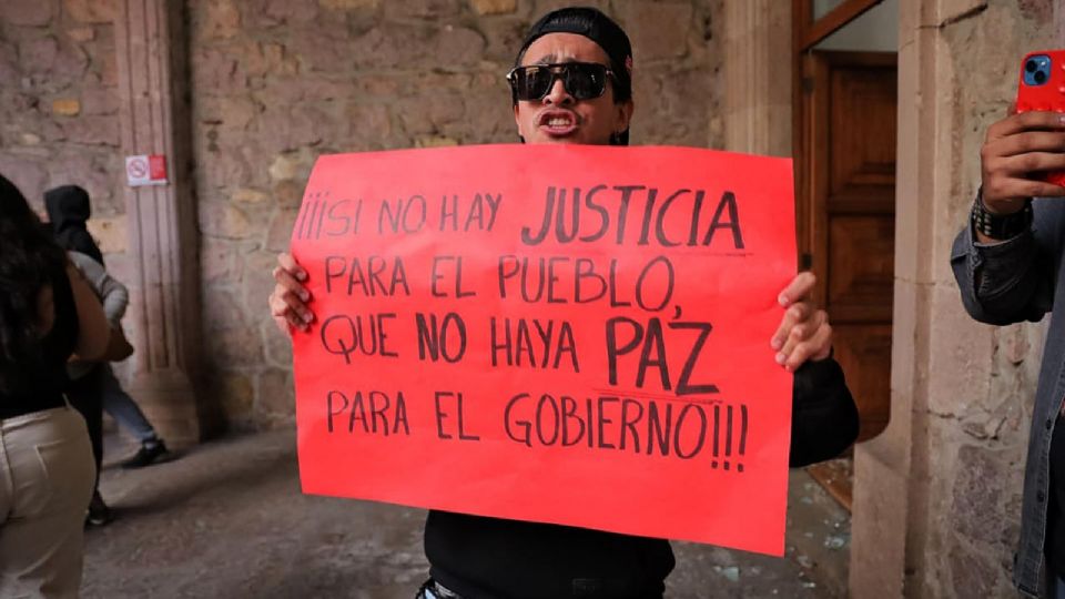 Una persona sostiene un cartel durante una manifestación este domingo, en el Palacio de Gobierno en Morelia.