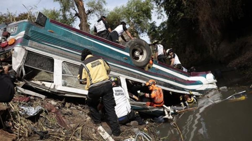 Bomberos trabajan en el sitio donde un autobús cayó en un río de aguas residuales en el norte de la Ciudad de Guatemala.