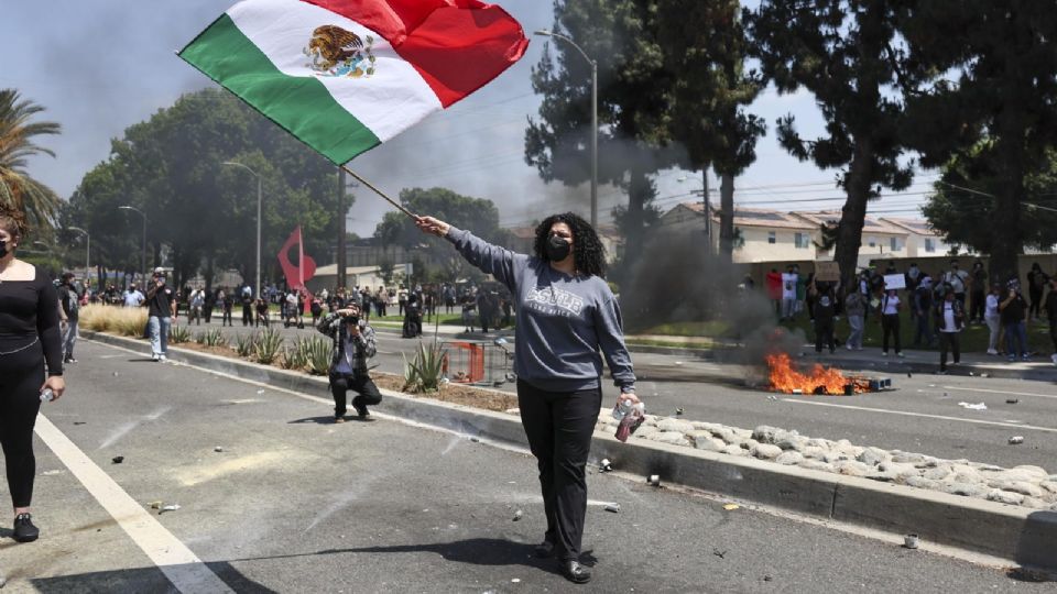 Fotografía del 7 de junio de una manifestante sosteniendo una bandera mexicana durante una protesta contra las redadas del Servicio de Inmigración y Control de Aduanas.