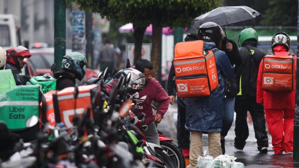 Repartidores de comida se estacionan frente una plaza comercial en Avenida Tláhuac.