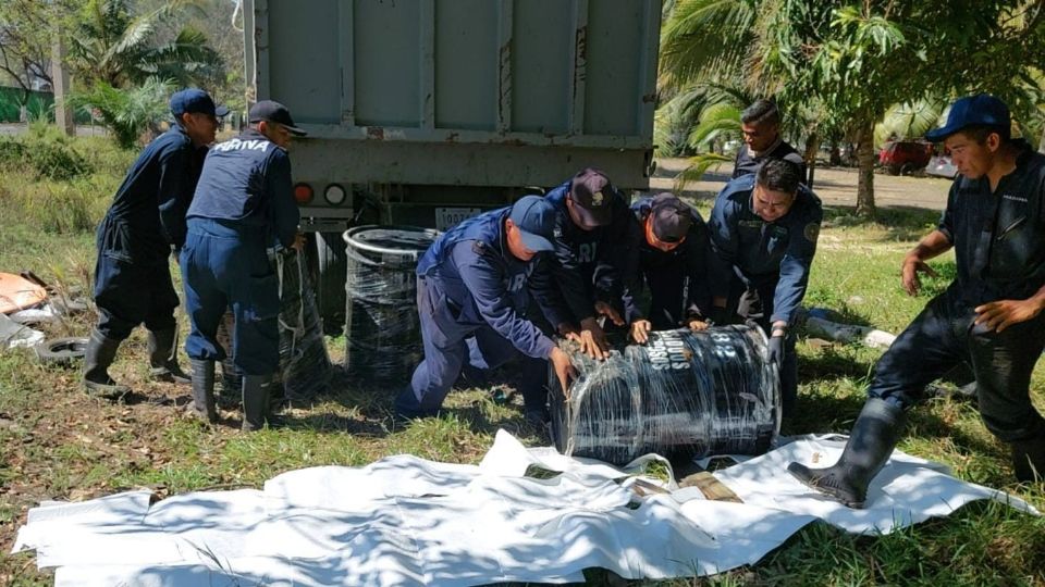 Personal naval y trabajadores civiles realizando labores coordinadas de saneamiento en las playas afectadas por el combustible.